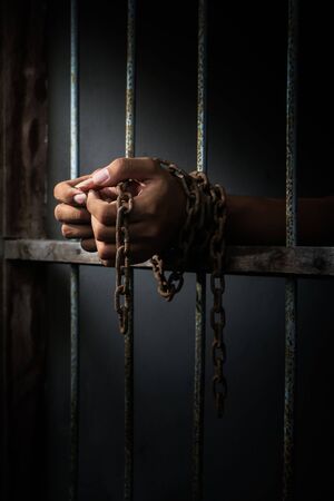 Close up hand of the prisoner on a steel lattice with rustic grunge chain