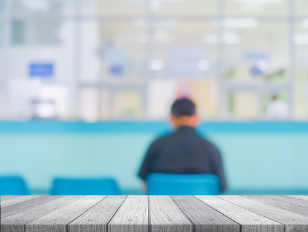 Wooden tabletop under blurred of picture people or patients in hospital waiting doctor or medicine.の写真素材
