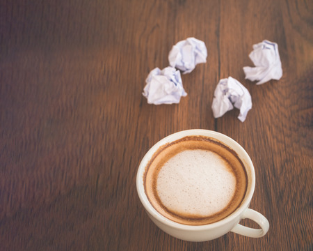 cup of coffee and crumpled paper on wooden tableの写真素材