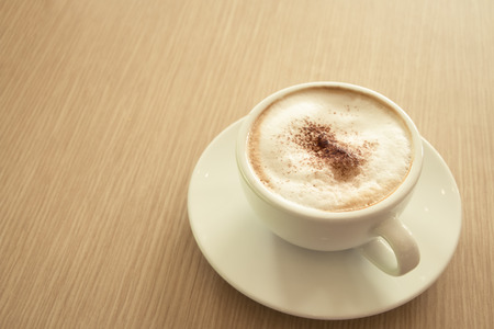 Cup of cappuccino coffee put on wooden tabletop at the shopの写真素材