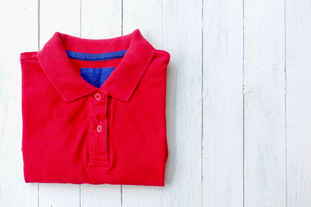 Red polo shirt put on white wooden tabletopの写真素材