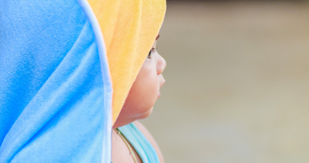 Close up cute baby with hood playing outdoorsの写真素材