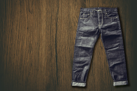 Close up top view of denim jeans trouser put on grunge rustic wooden table backgroundの写真素材