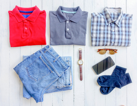 Men's clothes and accessories. Jeans, glasses, sock, smartphone on wooden background. Top view with...
