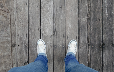 Close up man shoes with jeans walking on rustic wooden texture backgroundの写真素材