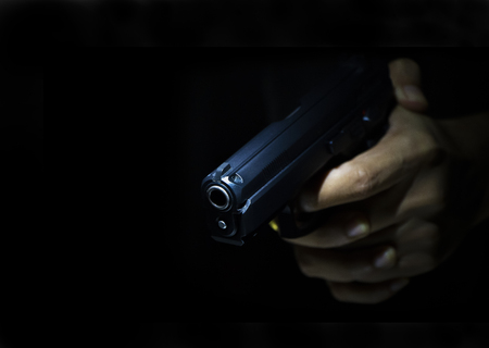 Close up male hand showing gesture try to kill someone with gun, Gunman with dark backgroundの写真素材