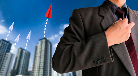 Red paper airplane with white other and building background with blue sky and clouds, Competition business concept.の写真素材