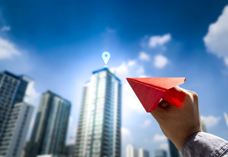 Business man in suit holding red paper airplane gesture to throwing with blurred image of building background and blue sky, Target on business concept.の写真素材