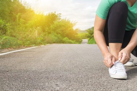 Asian woman holding rope shoes ready for running at the asphalt road in the morningの写真素材