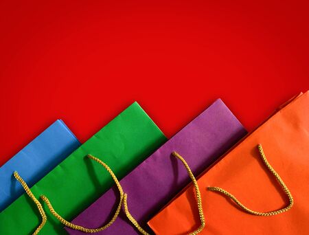 Close up top view of colorful paper shopping bag on red backgroundの写真素材