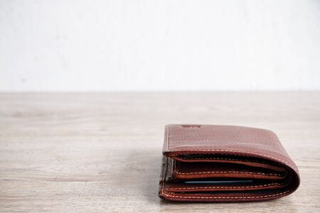 Close up brown leather luxury wallet put on wooden table backgroundの写真素材