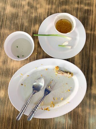 Close up dirty empty dish with spoon and fork put on tableの写真素材