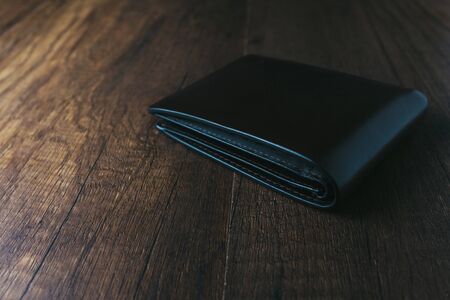 black leather wallet on wooden table