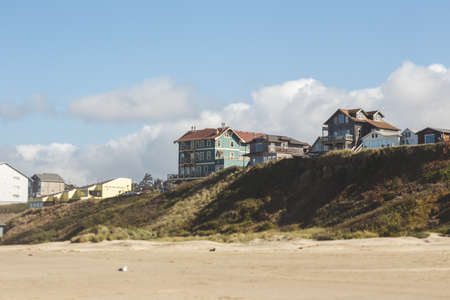 Modern houses sit on a ridge on a beach in Oregon. Partly cloudy summer day at Nye Beach, Newport, Oregon.の写真素材