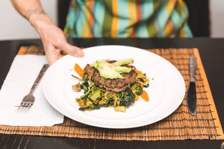 Chef holding plate full of freshly cooked veggies and meat.の写真素材