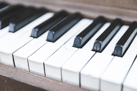 Black and white piano keys on a wooden upright piano.