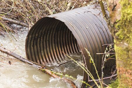 Metal water drain pipe in creek or river in a forest park. Vancouver, Washington, USA.の写真素材