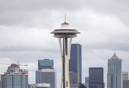 Seattle Space Needle in Seattle, Washington, USA. Sky scrapers and crane nearby with storm clouds above.のeditorial素材