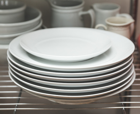 Dishes stacked on shelves in a kitchen area.の写真素材