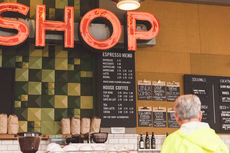 Cafe menu on wall with customer at counter in modern upscale cafe.の写真素材
