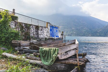 Boat dock in foreground and cloud-covered volcanic mountains in the distance at Lake Atitlan, Guatemala, Central America.の写真素材