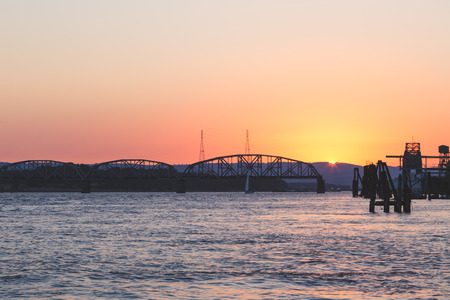 An open train bridge at sunset to allow a sailboat to pass through.の写真素材