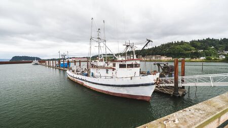 White and red fishing or crabbing boat in a slip at a marina.の写真素材