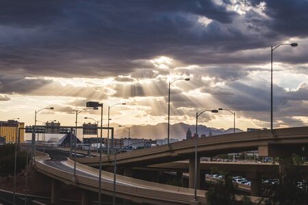 Sun rays shining through a cloudy sky over a superhighway scene in the city of Las Vegas.の写真素材