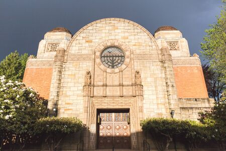 Front view of Temple Beth Israel in sunlight with a dark sky background.の写真素材