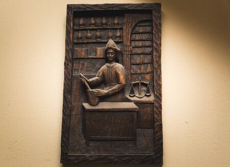 Wooden art piece with Spanish-looking merchant man or shopkeeper in a store or market setting.のeditorial素材