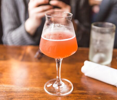Amber or reddish-orange kombucha drink in a nice glass. Restaurant table setting.の写真素材