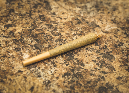 Pre-rolled joint or cigarette sitting on a textured counter top.の写真素材