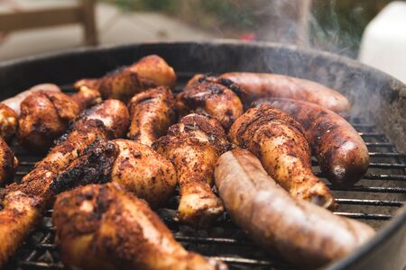 Meat cooking on a grill with spices and seasonings on it. Chicken and beef or pork brats.の写真素材