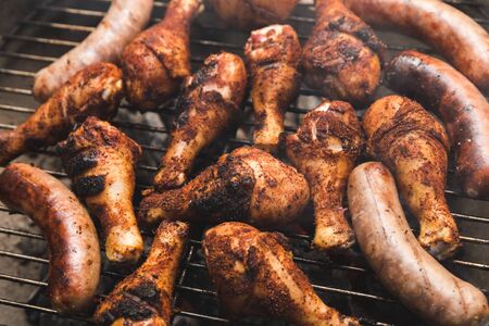 Meat cooking on a grill with spices and seasonings on it. Chicken and beef or pork brats.の写真素材