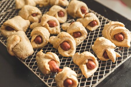 Sausages wrapped in dough and baked, also known as "pigs in a blanket", on a metal cooking rack.の写真素材