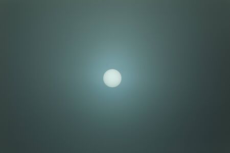 The sun appearing as a distinct ball behind clouds.の写真素材