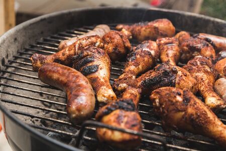Meat cooking on a grill with spices and seasonings on it. Chicken and beef or pork brats.の写真素材