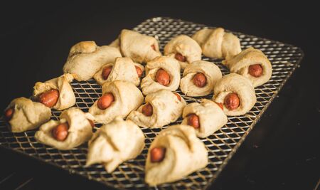 Sausages wrapped in dough and baked, also known as "pigs in a blanket", on a metal cooking rack.の写真素材