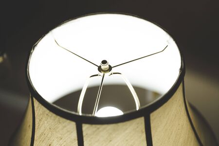 Table lamp with a dark shaded lampshade lit up inside a house.の写真素材