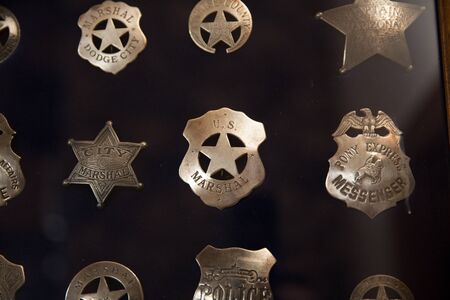 Collection of vintage or antique police badges inside a glass case.の写真素材