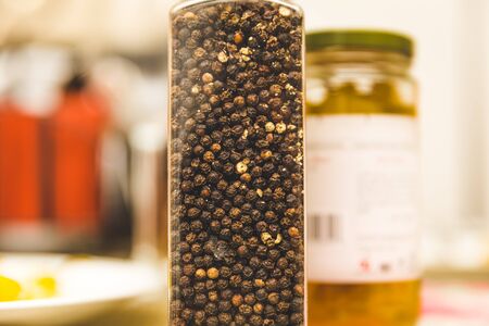 Peppercorns in a pepper grinder set on a dinner table.の写真素材