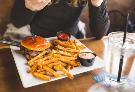 Woman just receiving a meal of hamburger and fries at a restaurant.の写真素材