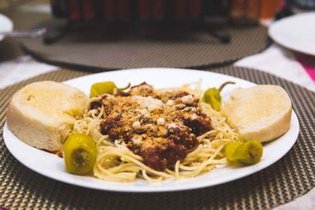Spaghetti with red meat sauce being served by the cook on a white dinner plate.の写真素材