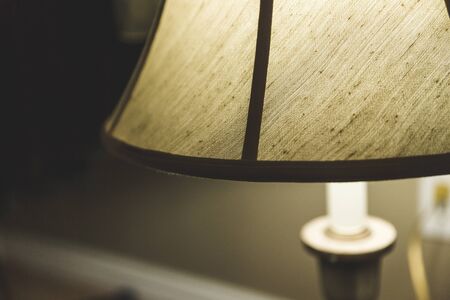 Table lamp with a dark shaded lampshade lit up inside a house.の写真素材