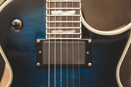 Portion of the neck and body of an electric guitar showing the strings, fretboard and pickup.の写真素材