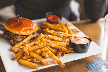 Woman just receiving a meal of hamburger and fries at a restaurant.の写真素材