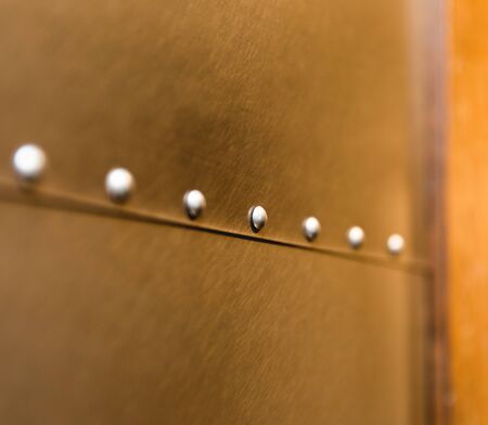 Smooth, round rivets on the side of a piece of furniture made with sheets of stainless steel metal.の写真素材