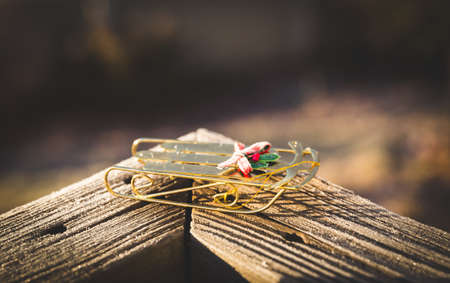 Small golden sleigh Christmas ornament sitting on a wooden railing.の写真素材