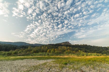 Puffy clouds in a blue sky over green and rocky landscape in the Columbia River Gorge, Washington, USA.の写真素材