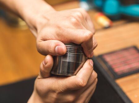 Hands twisting the cap of a steel grinder made for cannabis (marijuana) buds.の写真素材